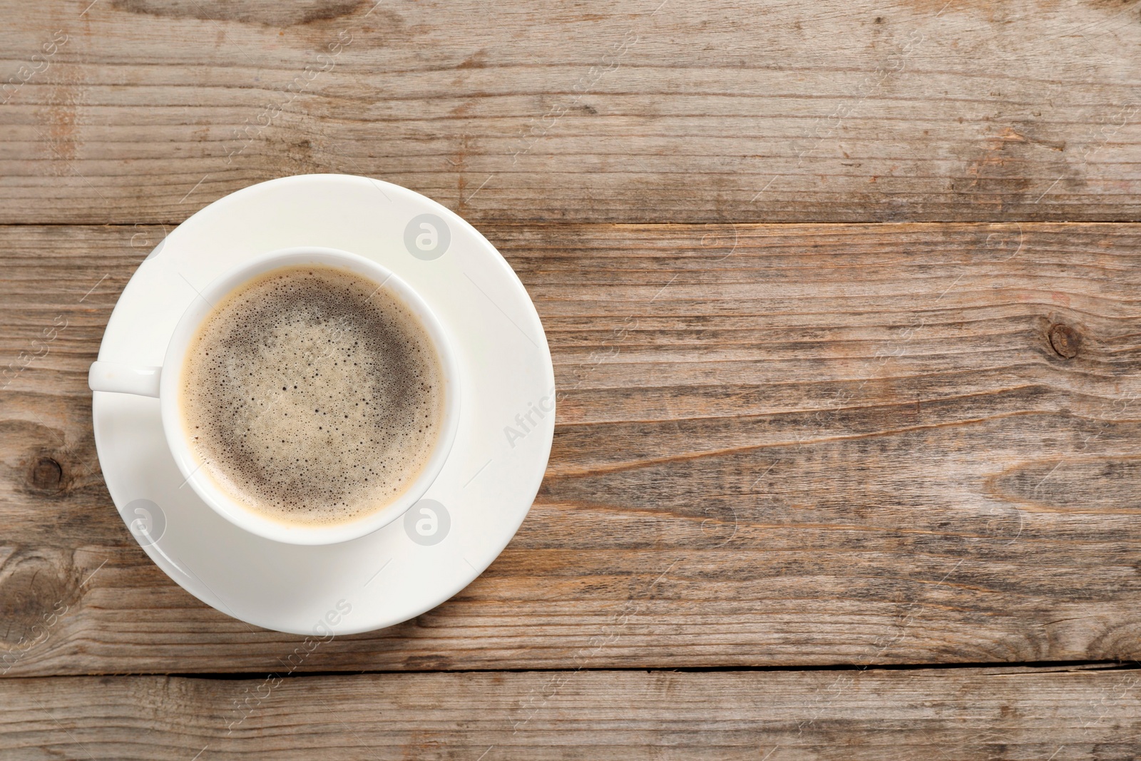 Photo of Tasty coffee in cup on wooden table, top view. Space for text