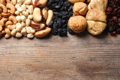 Photo of Different dried fruits and nuts on wooden background, top view. Space for text