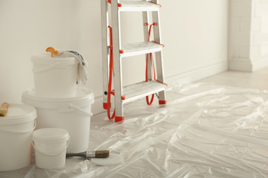 Photo of Stepladder and different tools near wall in room. Interior renovation