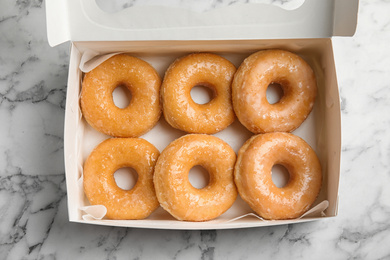 Photo of Delicious donuts on marble table, top view