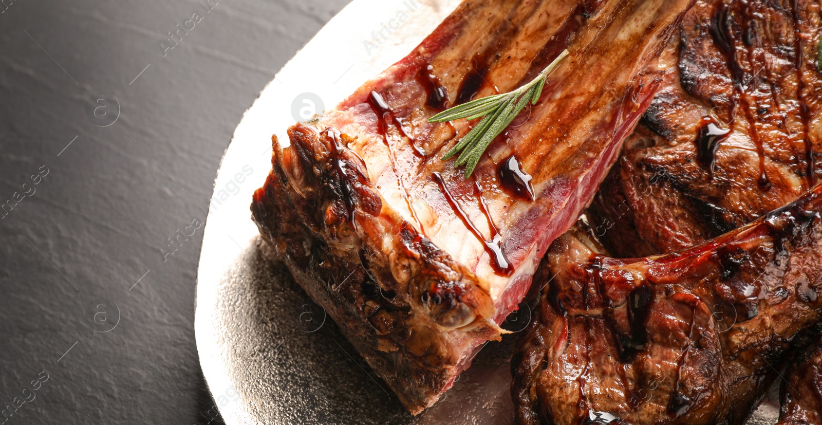 Image of Delicious grilled ribs with rosemary on table, closeup. Banner design