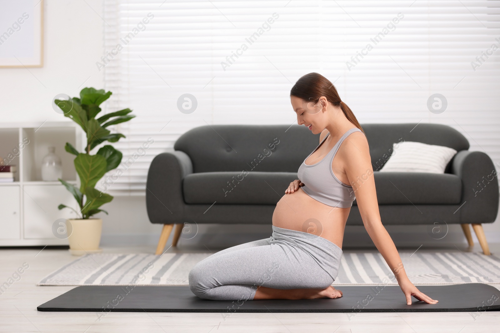 Photo of Pregnant woman doing exercises on yoga mat at home