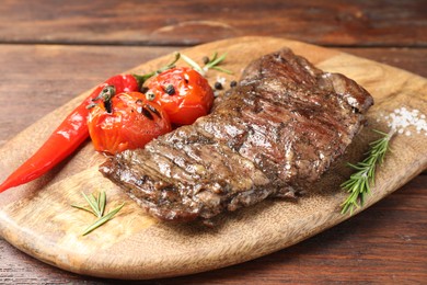 Delicious roasted beef meat, vegetables and spices on wooden table