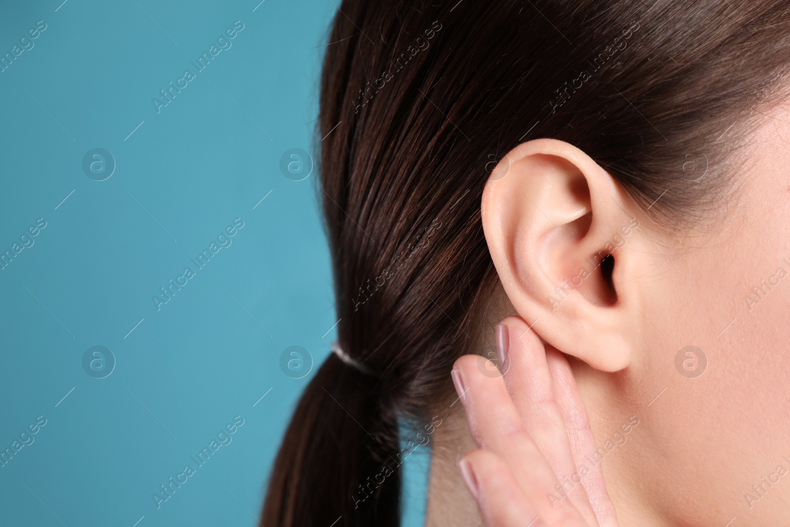 Photo of Woman showing hand to ear gesture on light blue background, closeup. Space for text