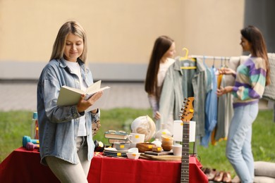 Women choosing items on garage sale in yard