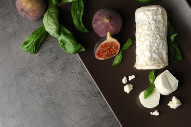 Delicious goat cheese with figs and basil on grey table, above view. Space for text