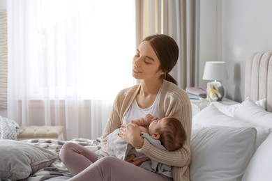 Young woman with her little baby on bed at home