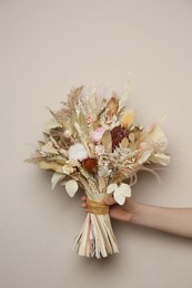 Photo of Woman holding beautiful dried flower bouquet on beige background, closeup