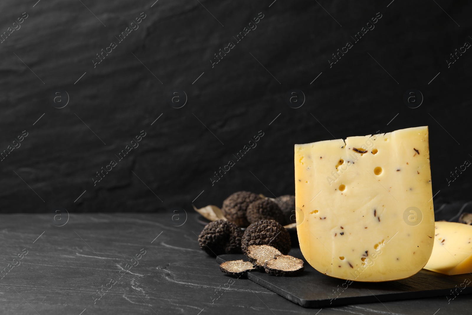 Photo of Fresh cheese and truffles on black table. Space for text