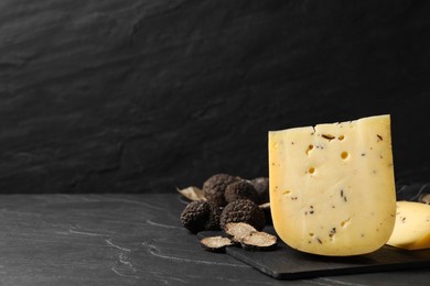 Photo of Fresh cheese and truffles on black table. Space for text