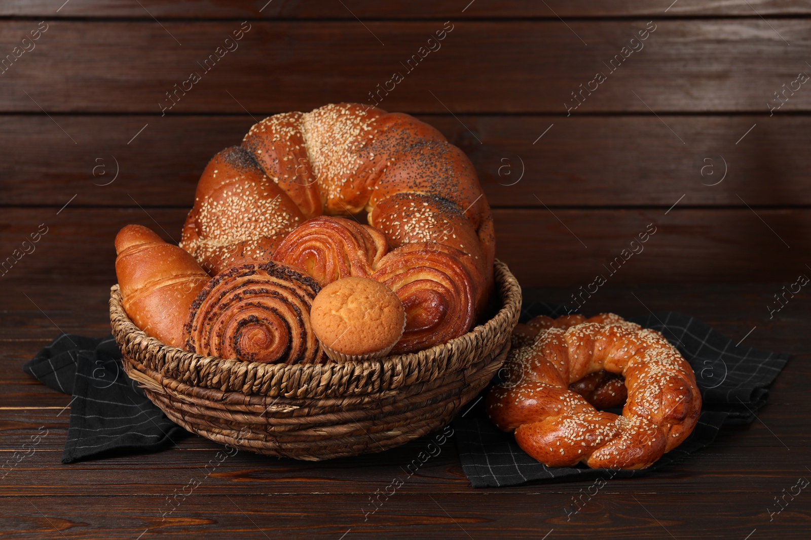 Photo of Wicker basket with different tasty freshly baked pastries on wooden table