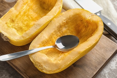 Wooden board with cut spaghetti squash on table