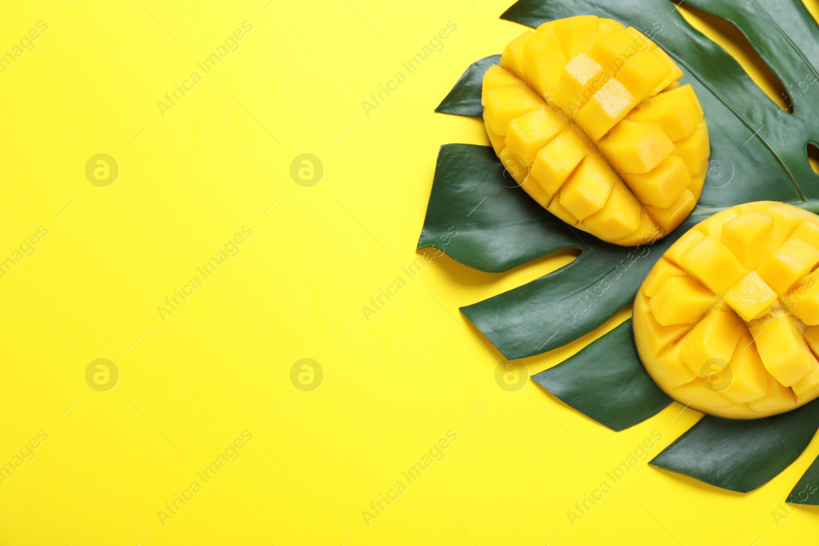 Photo of Cut fresh ripe mango and leaf on yellow background, flat lay. Space for text