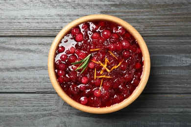 Fresh cranberry sauce with orange peel and rosemary on grey wooden table, top view