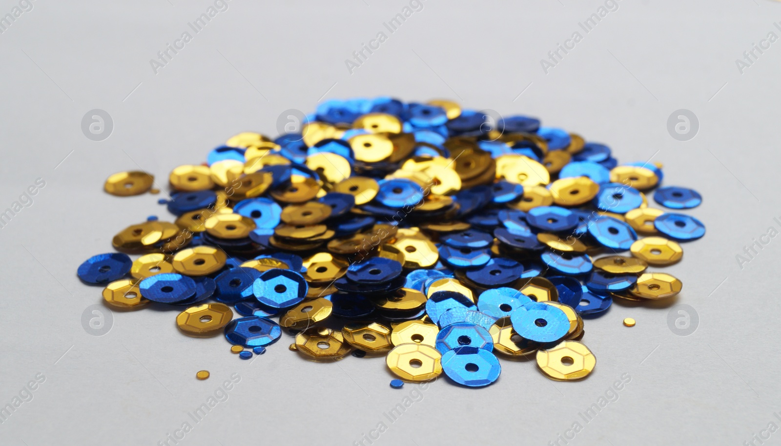 Photo of Pile of colorful sequins on light grey background, closeup