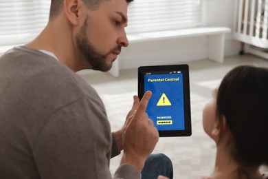 Photo of Dad installing parental control on tablet at home, closeup. Child safety