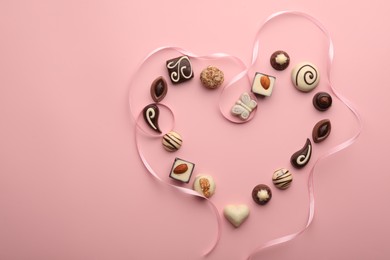 Heart made with delicious chocolate candies on light pink background, flat lay. Space for text