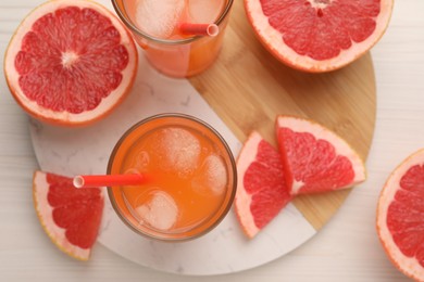 Tasty freshly made grapefruit juice and fruits on white wooden table, top view