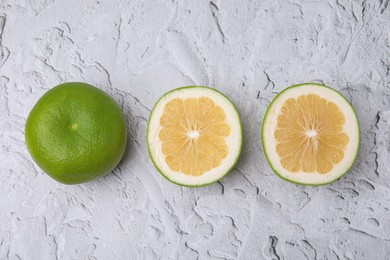 Whole and cut sweetie fruits on textured table, flat lay