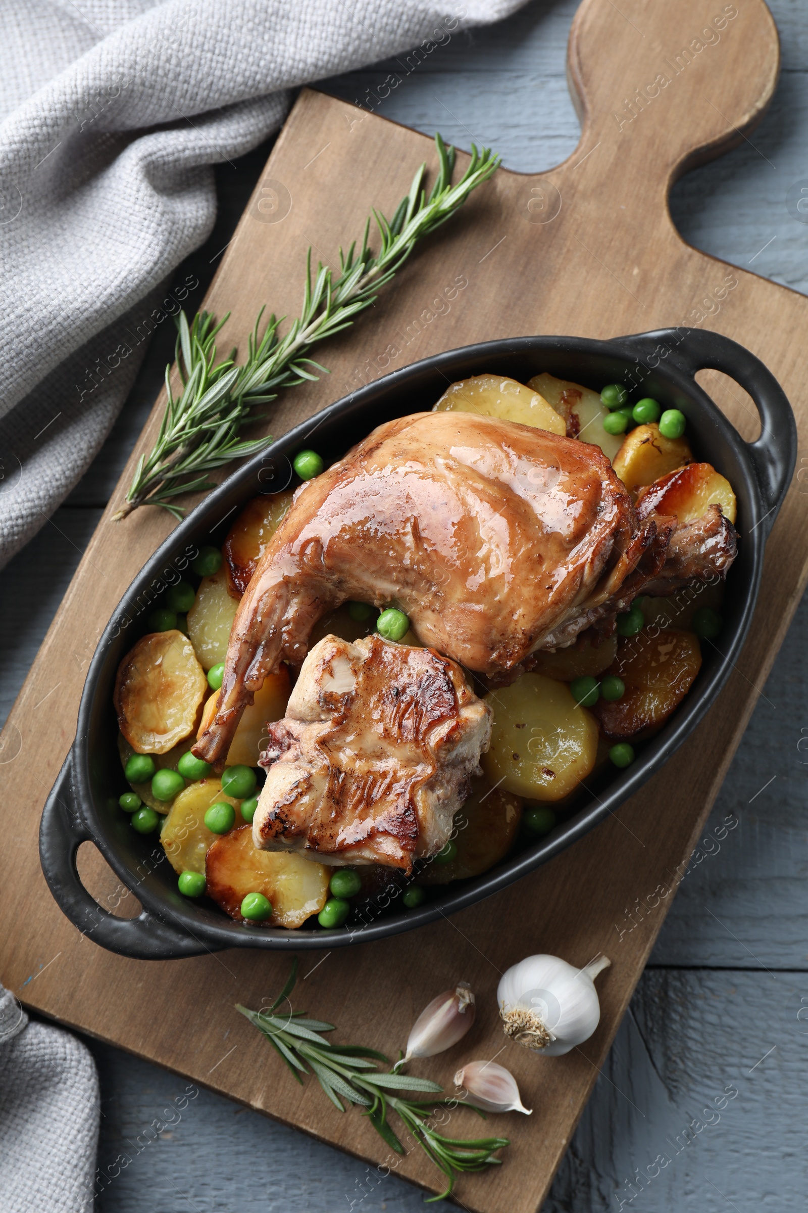 Photo of Tasty cooked rabbit with vegetables in baking dish on grey wooden table, top view