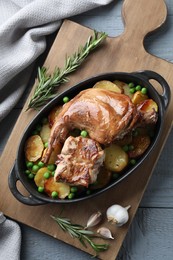 Photo of Tasty cooked rabbit with vegetables in baking dish on grey wooden table, top view