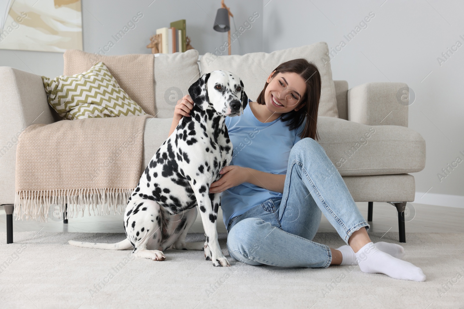 Photo of Happy young woman with her adorable Dalmatian dog at home. Lovely pet