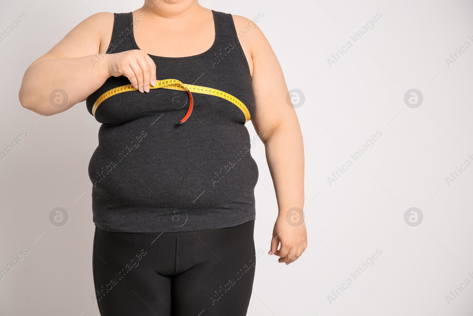 Photo of Overweight woman with measuring tape on light background