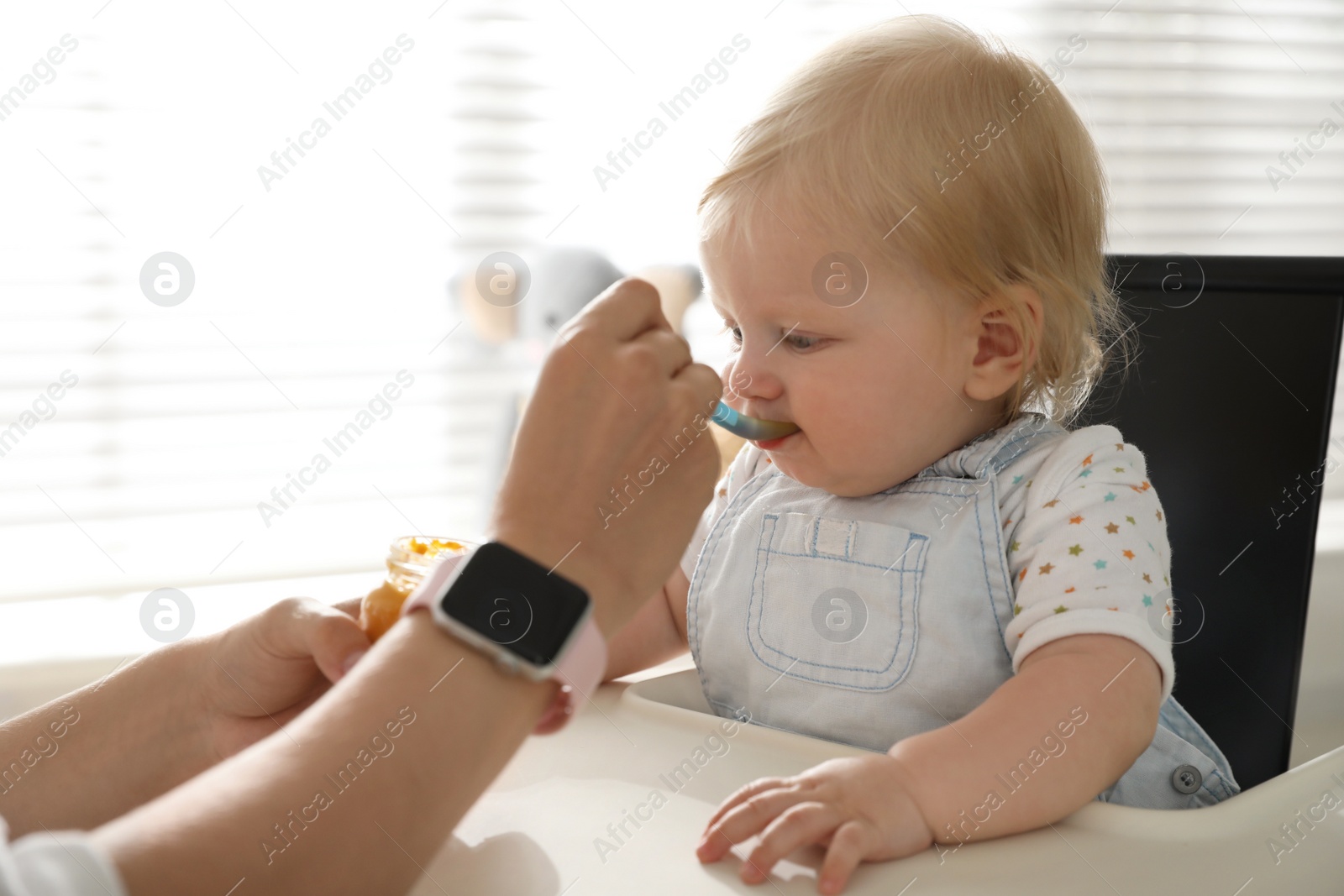 Photo of Mother feeding her cute little baby with healthy food at home