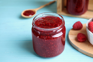 Photo of Delicious raspberry jam on light blue wooden table, closeup