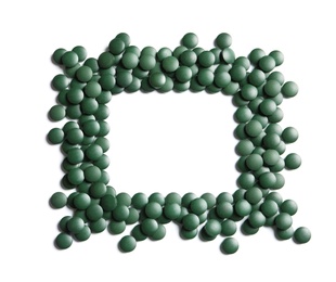 Photo of Frame of green spirulina pills on white background, top view with space for text