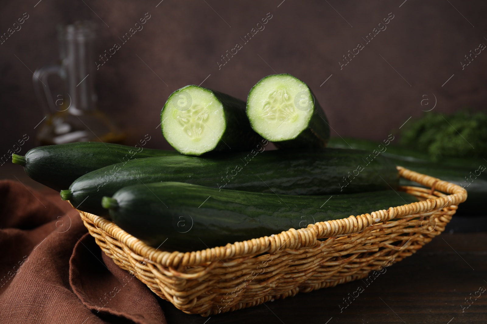 Photo of Fresh cucumbers in wicker basket on table, closeup