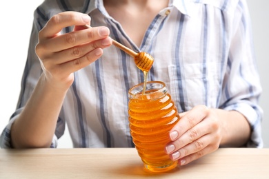 Photo of Woman with jar of honey at wooden table, closeup