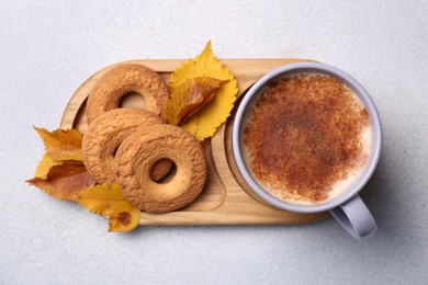 Photo of Cup of hot drink, cookies and autumn leaves on light grey textured table, top view