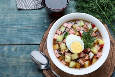 Delicious cold okroshka with kvass served on blue wooden table, flat lay. Traditional Russian summer soup