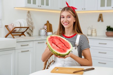 Photo of Beautiful teenage girl with half of watermelon in kitchen