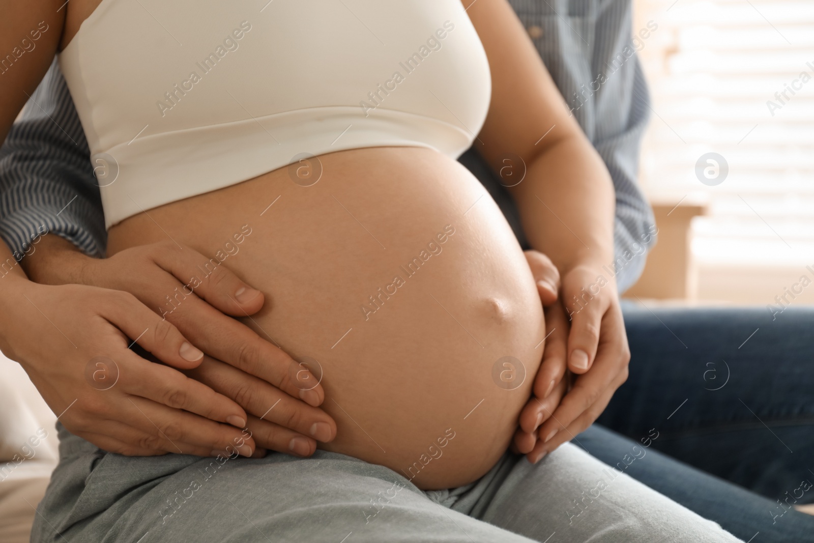 Photo of Man touching his pregnant wife's belly at home, closeup