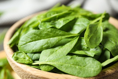 Photo of Fresh green healthy spinach in wooden bowl, closeup