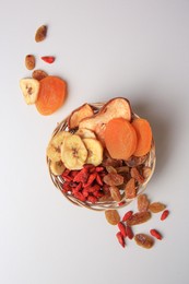 Photo of Wicker basket with different dried fruits on white background, top view