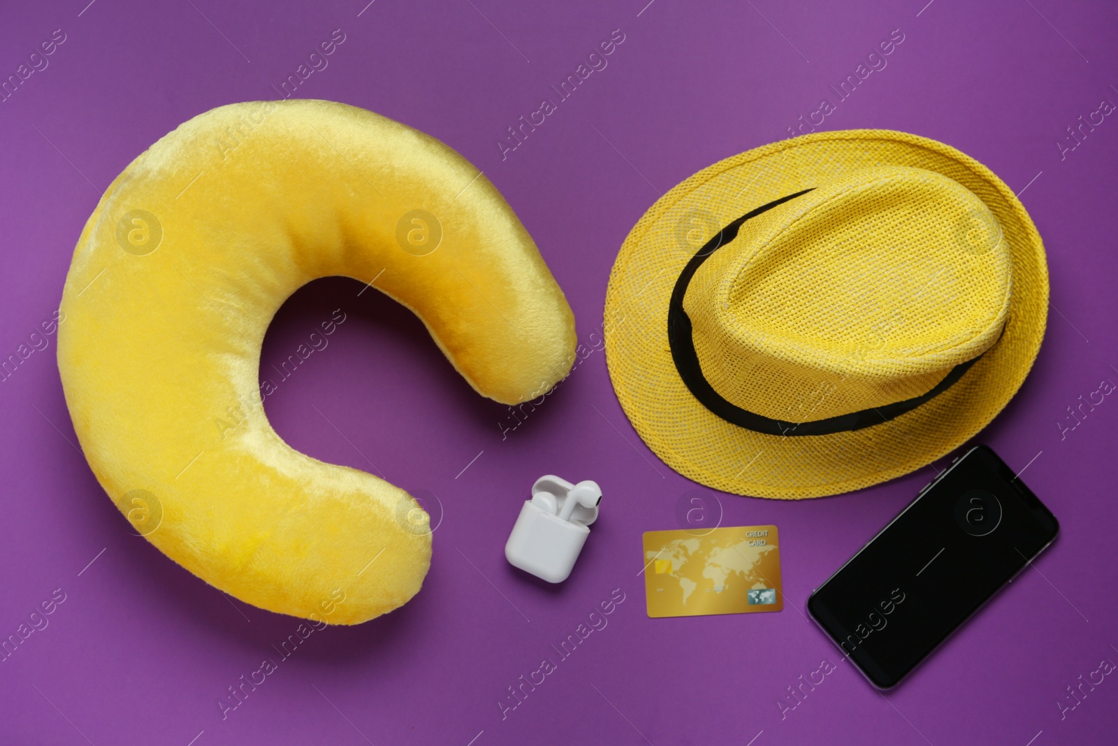 Photo of Flat lay composition with yellow travel pillow and smartphone on purple background