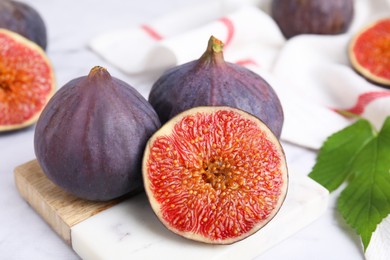 Photo of Fresh ripe purple figs on white table, closeup