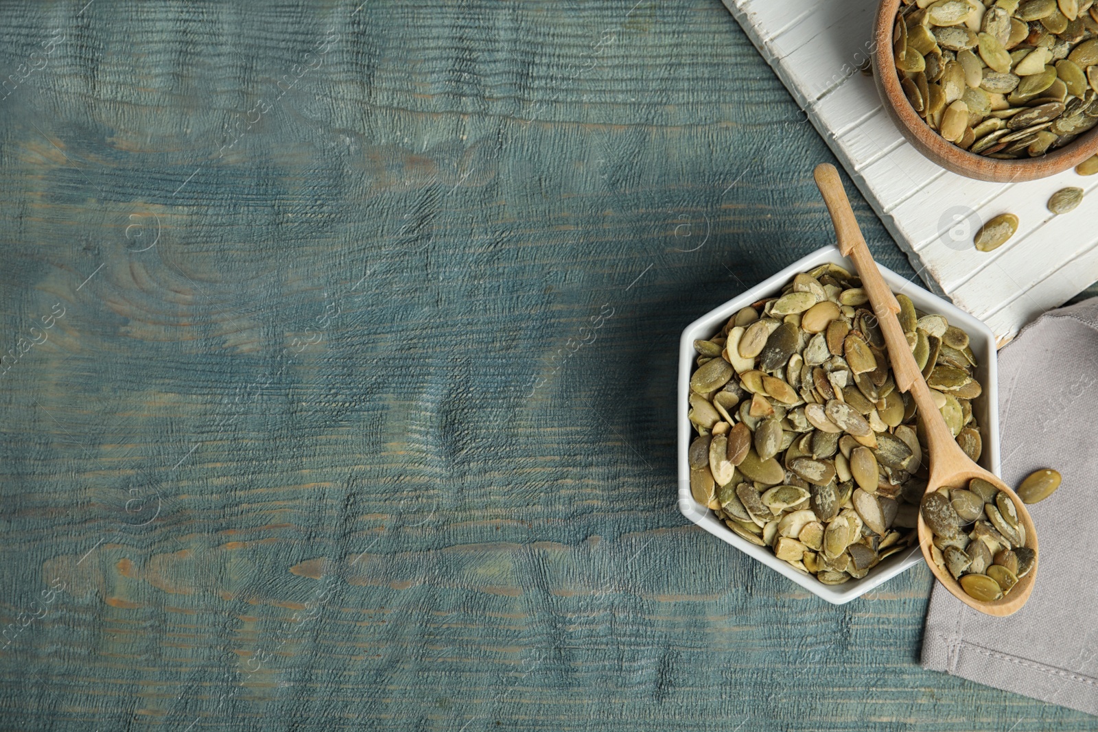 Photo of Flat lay composition with raw pumpkin seeds on blue wooden table, space for text