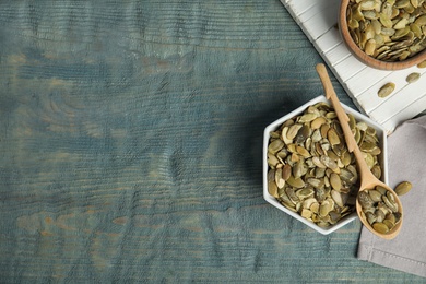 Photo of Flat lay composition with raw pumpkin seeds on blue wooden table, space for text