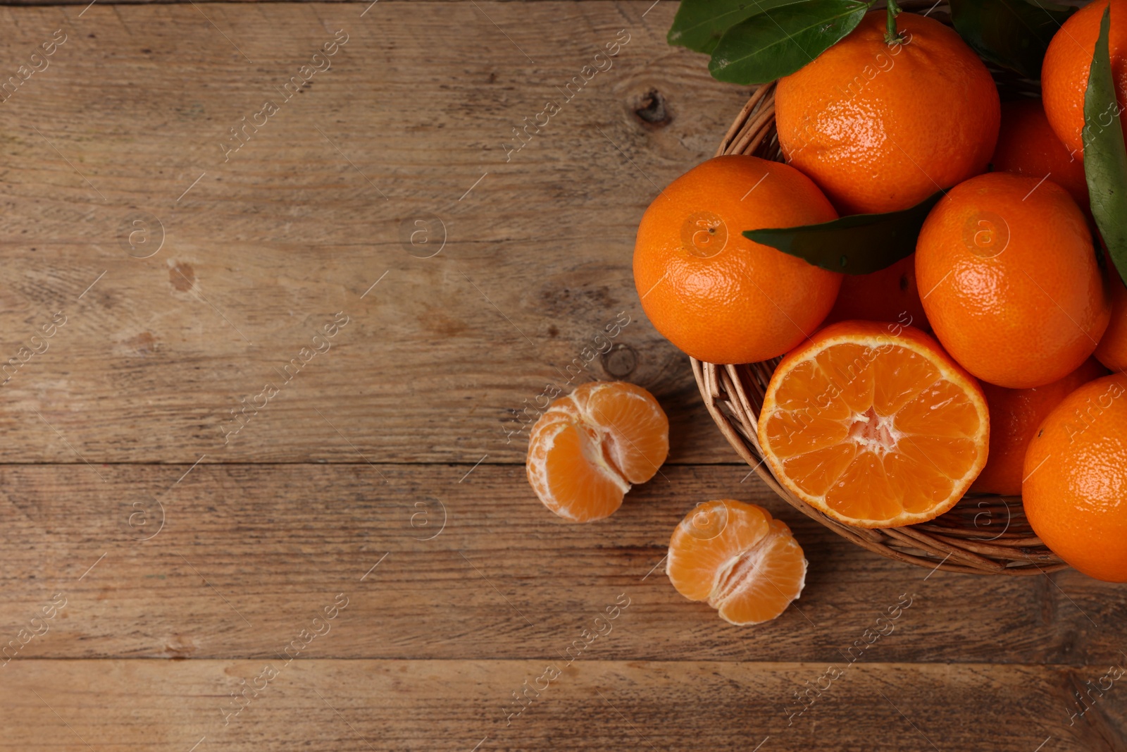 Photo of Delicious tangerines with leaves on wooden table, top view. Space for text