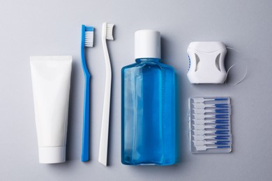 Photo of Flat lay composition with fresh mouthwash in bottle and other oral care products on grey background