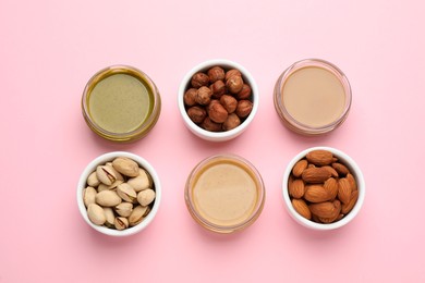 Photo of Different types of delicious nut butters and ingredients on pink background, flat lay