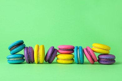 Photo of Delicious colorful macarons on green background. Space for text
