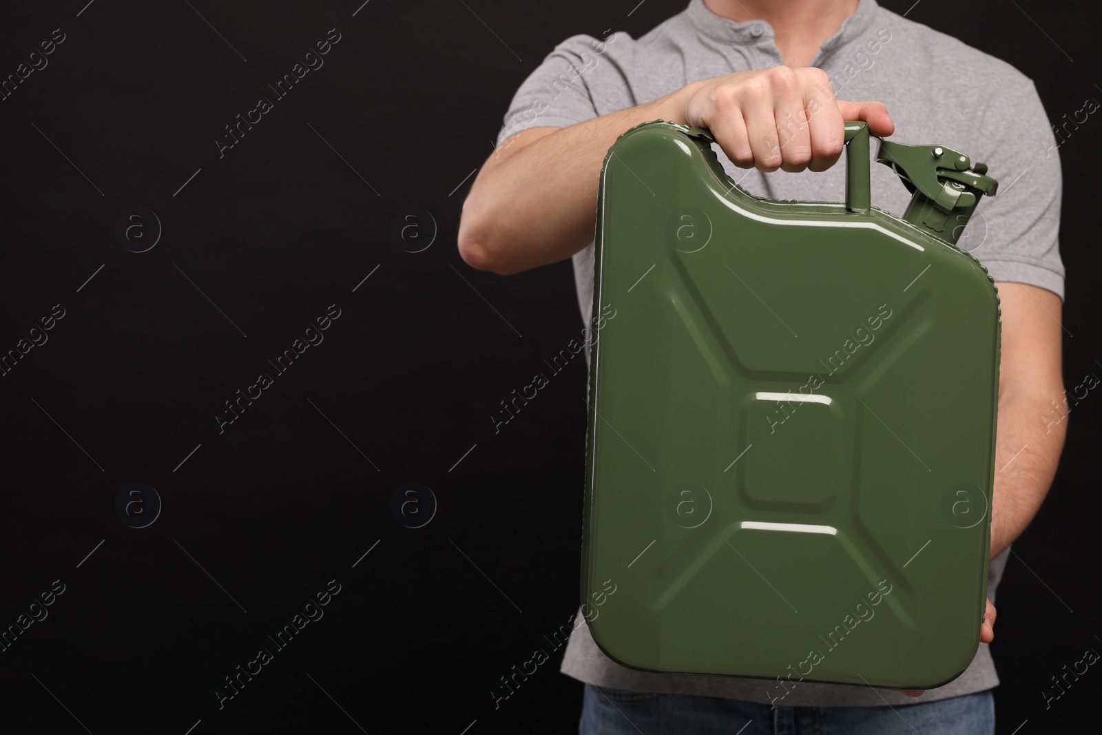 Photo of Man holding khaki metal canister on black background, closeup. Space for text