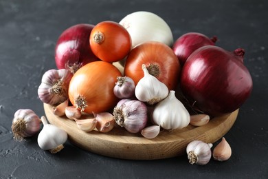 Photo of Fresh raw garlic and onions on black table, closeup