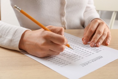 Student filling answer sheet at table, closeup