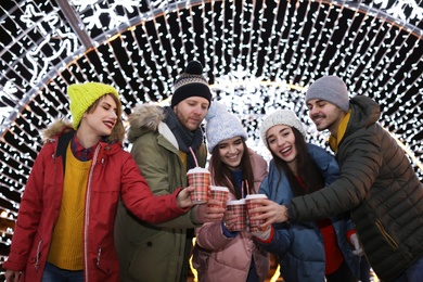 Happy friends with cups of mulled wine at winter fair